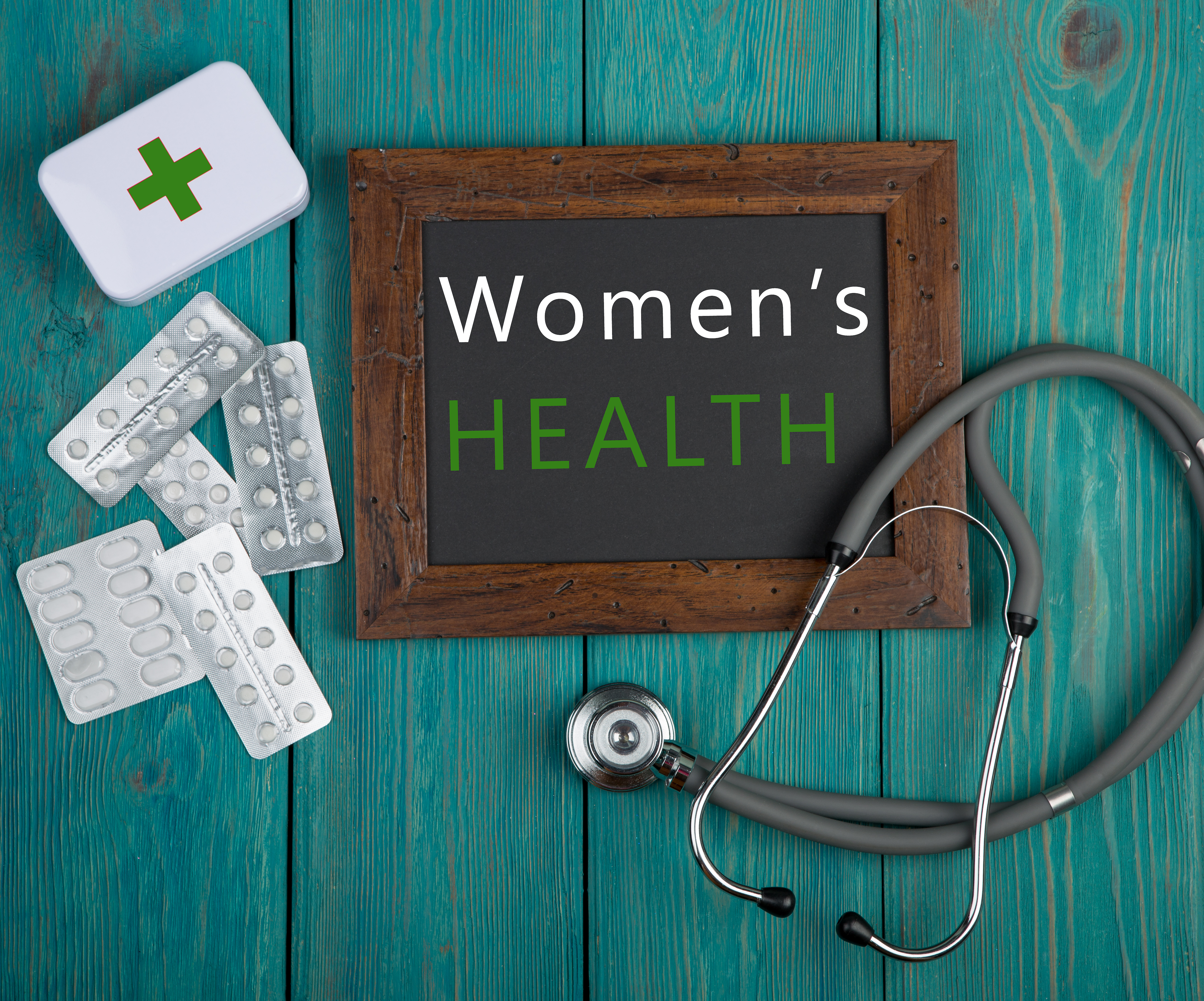 Blackboard with text “Women’s health”, stethoscope, pills